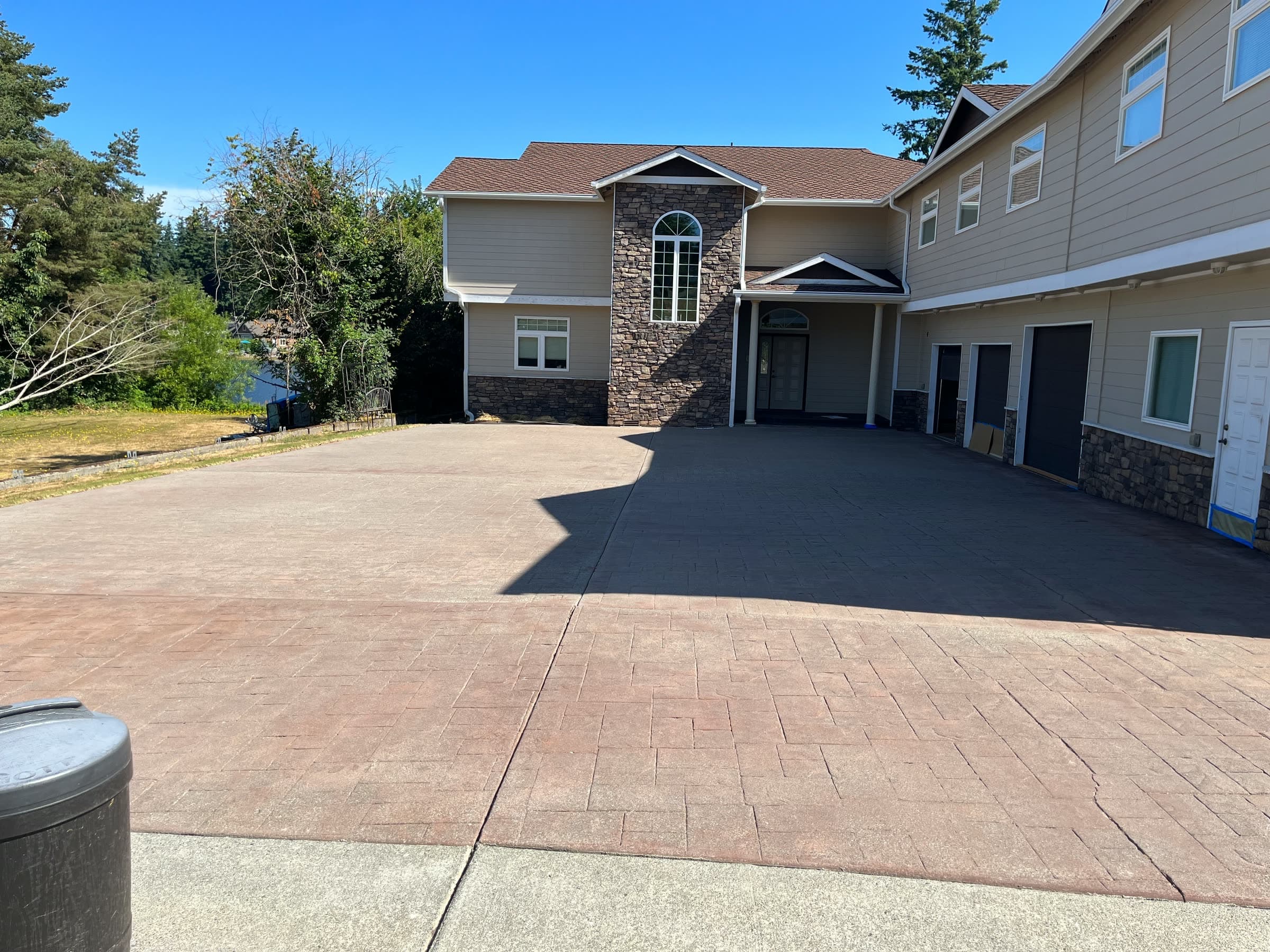 A long patterned concrete driveway, cleaned and sealed, leading to a large two-storey house.