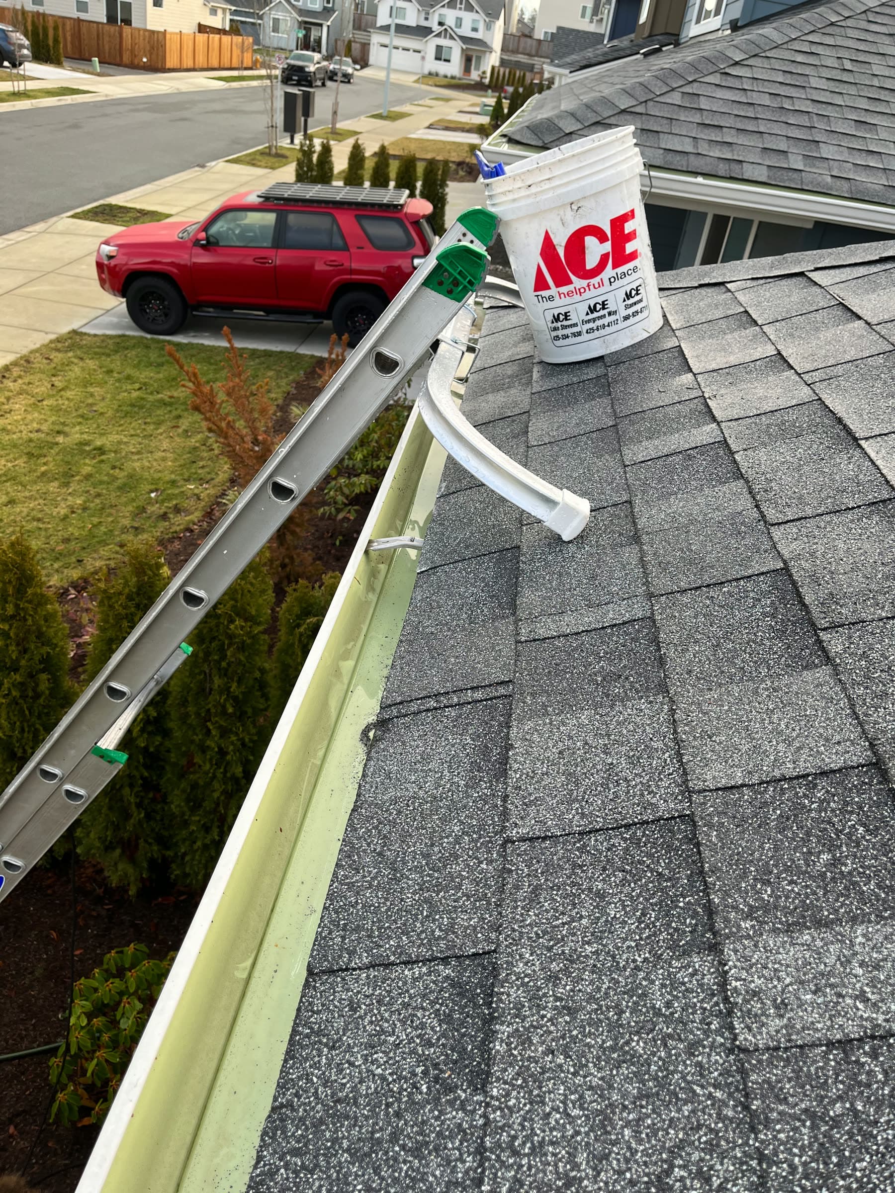 The same gutter cleaned out, a bucket hanging from the ladder.