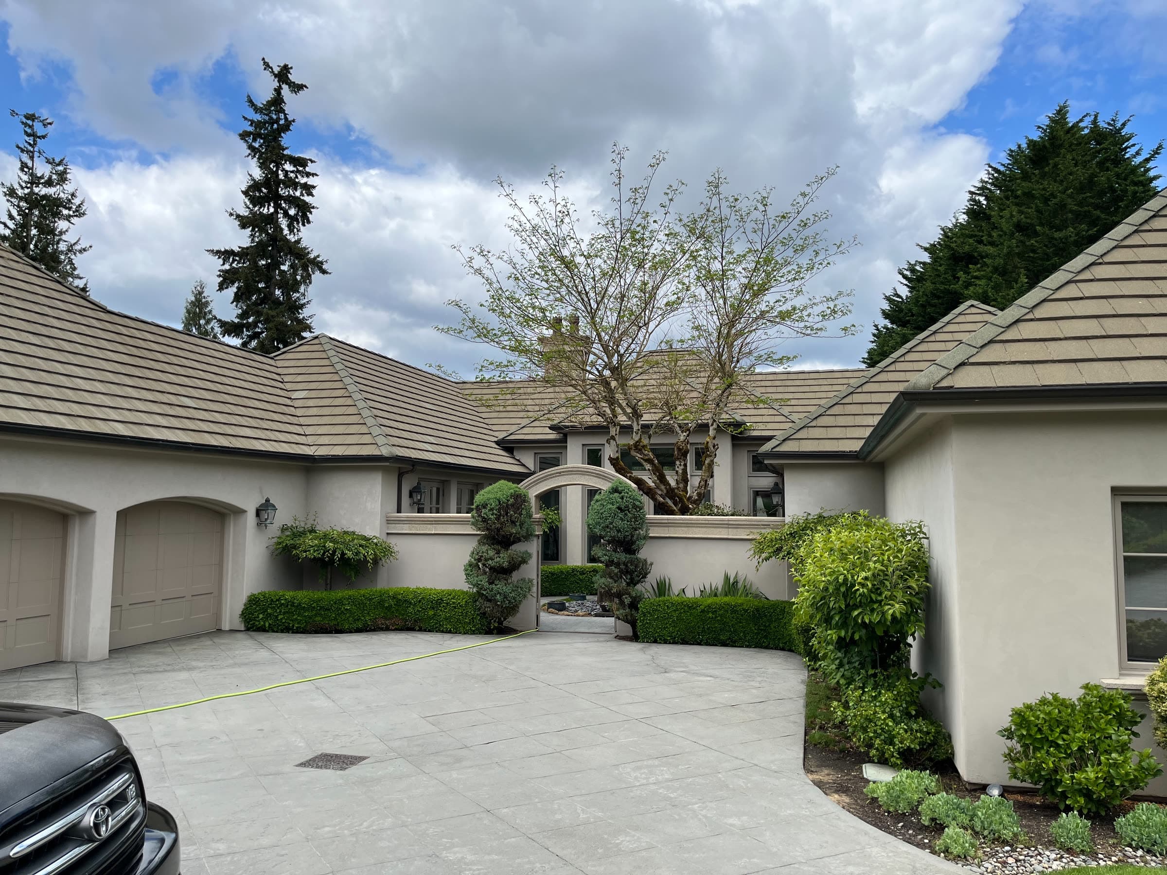 A tile-roofed house around a courtyard driveway, the stamped concrete clean and dry.
