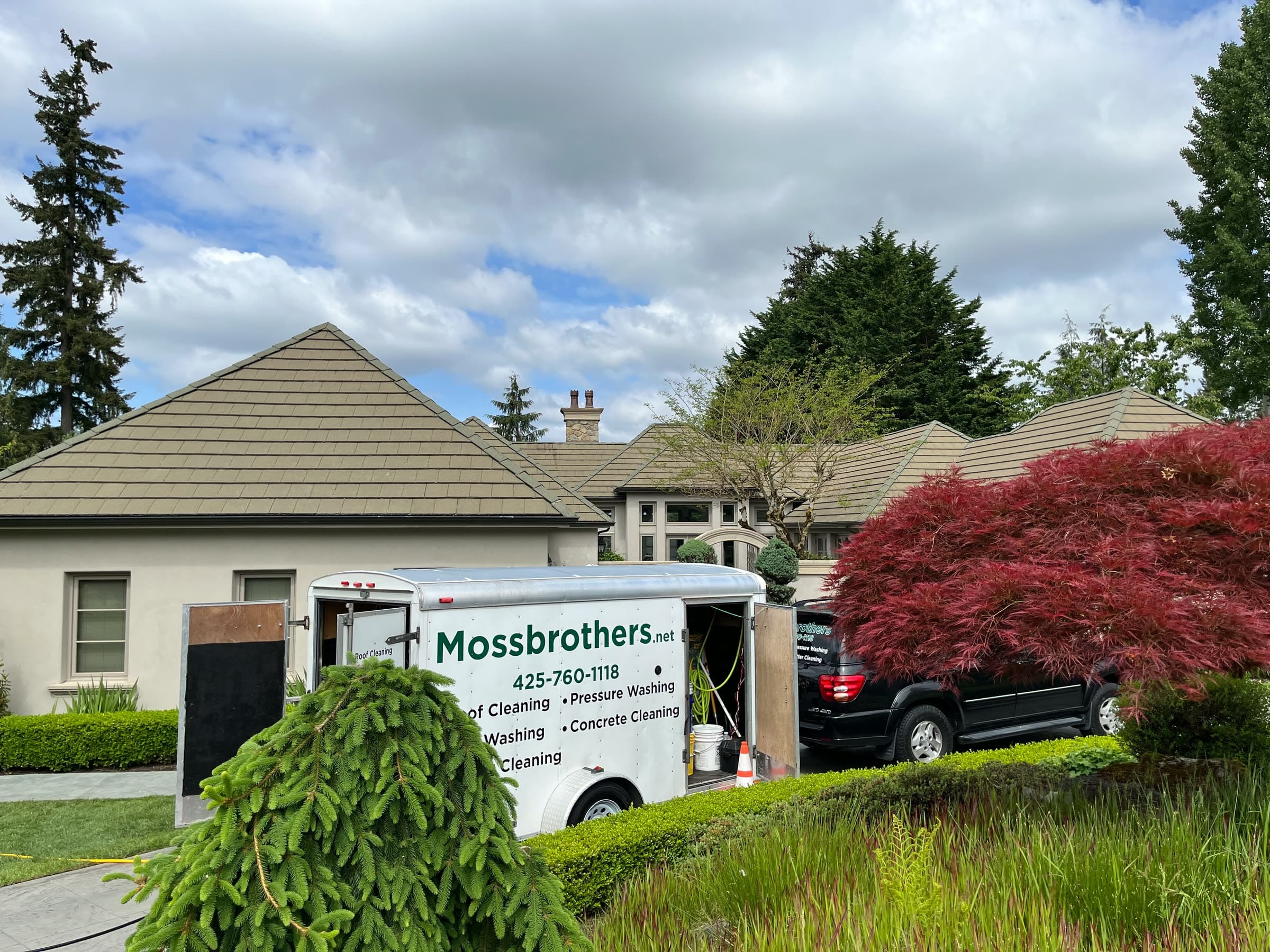 A tile-roofed house with the Mossbrothers trailer parked out front beside a red Japanese maple.
